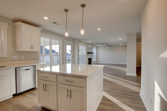 kitchen with ceiling fan, a center island, stainless steel dishwasher, plenty of natural light, and white cabinets