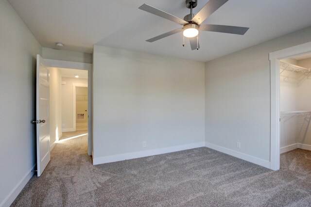 unfurnished bedroom with a walk in closet, light colored carpet, a closet, and ceiling fan