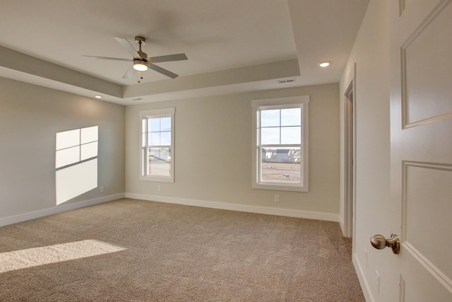 carpeted spare room featuring ceiling fan and a raised ceiling