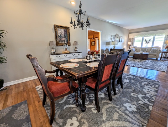 dining room with dark wood-type flooring and an inviting chandelier