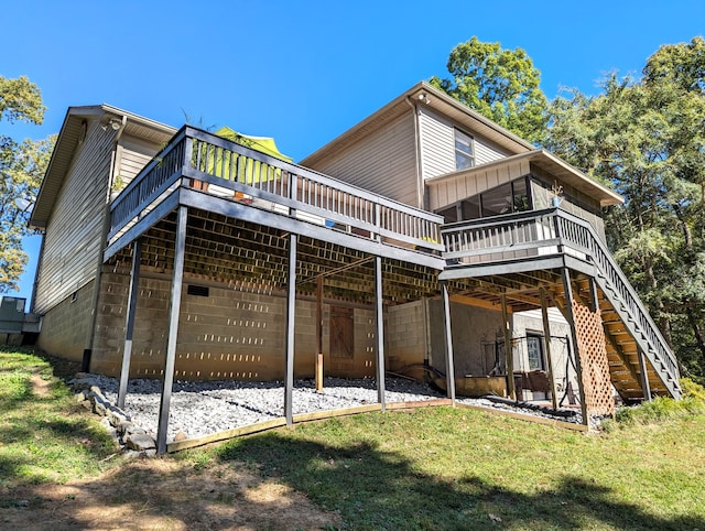 back of house featuring a sunroom, a deck, and a lawn