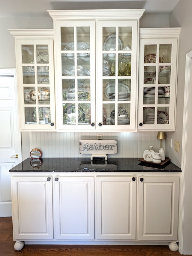 bar with white cabinets, dark hardwood / wood-style floors, and dark stone counters