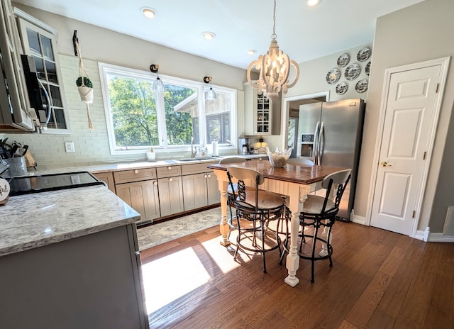 kitchen featuring sink, hanging light fixtures, dark wood-type flooring, light stone counters, and a chandelier