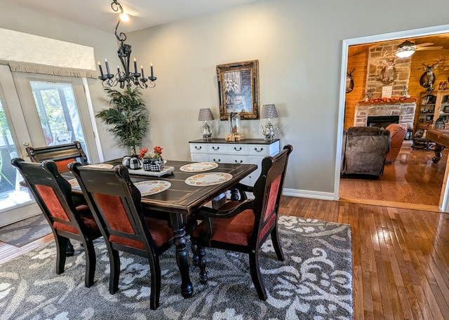 dining room with hardwood / wood-style flooring and a stone fireplace