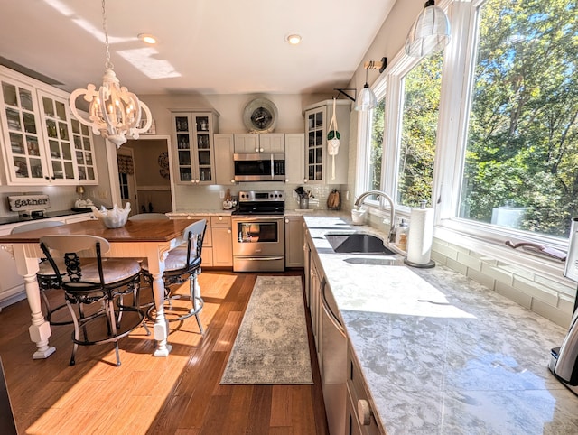 kitchen featuring decorative light fixtures, light hardwood / wood-style floors, light stone counters, and stainless steel appliances