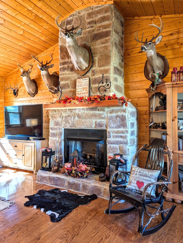 living room featuring hardwood / wood-style floors, wooden walls, vaulted ceiling, a fireplace, and wood ceiling