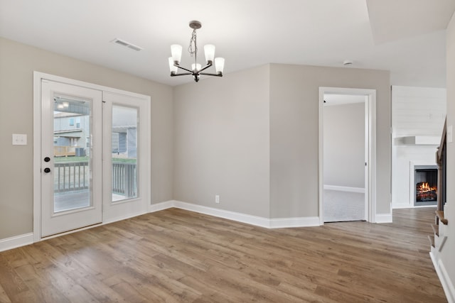 unfurnished dining area featuring a chandelier and hardwood / wood-style flooring