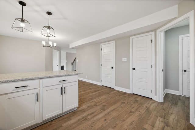 kitchen featuring light stone countertops, dark hardwood / wood-style flooring, decorative light fixtures, a chandelier, and white cabinetry