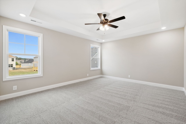 carpeted empty room with a tray ceiling and ceiling fan