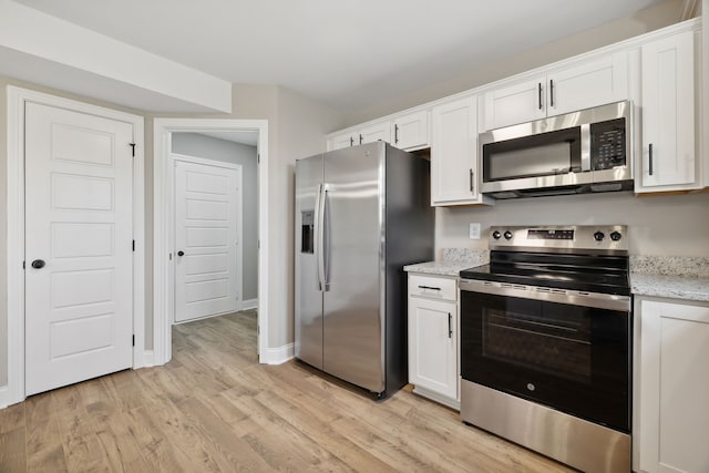 kitchen with white cabinets, light stone counters, light wood-type flooring, and stainless steel appliances