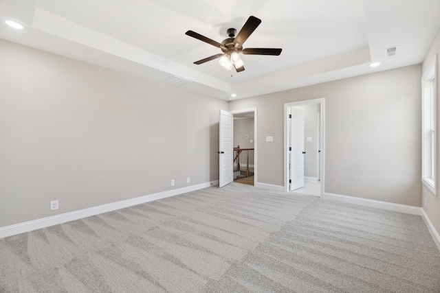 unfurnished bedroom with light colored carpet, a raised ceiling, and ceiling fan