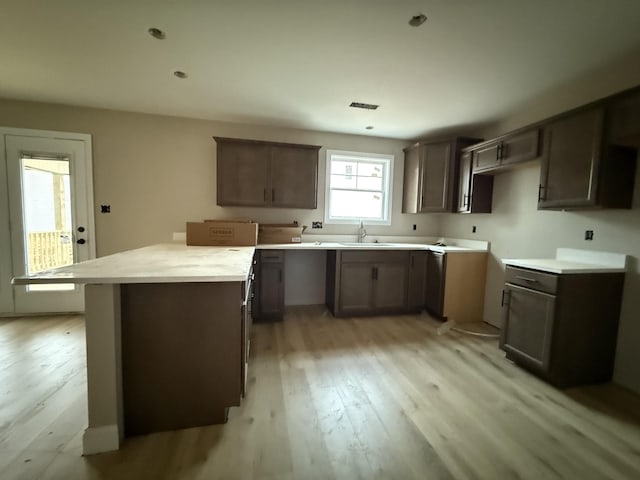 kitchen with a center island, dark brown cabinetry, light hardwood / wood-style floors, and sink