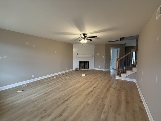 unfurnished living room featuring a large fireplace, ceiling fan, and light hardwood / wood-style flooring