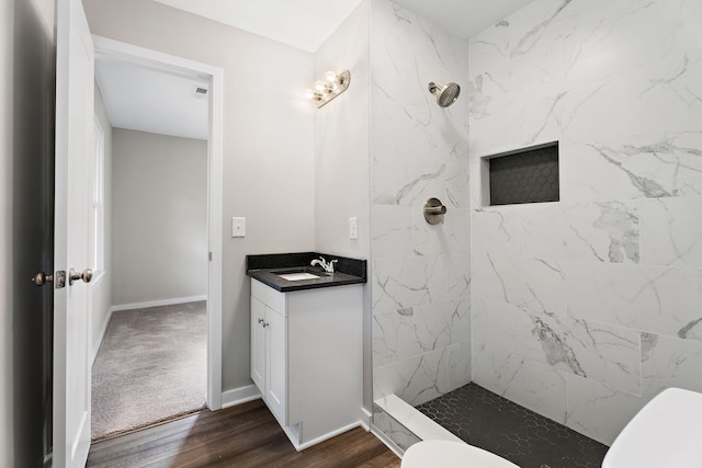 bathroom featuring vanity, hardwood / wood-style floors, a tile shower, and toilet