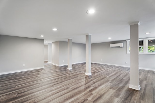 basement featuring a wall mounted air conditioner and wood-type flooring