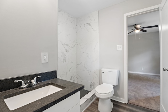 bathroom featuring toilet, hardwood / wood-style floors, vanity, a tile shower, and ceiling fan