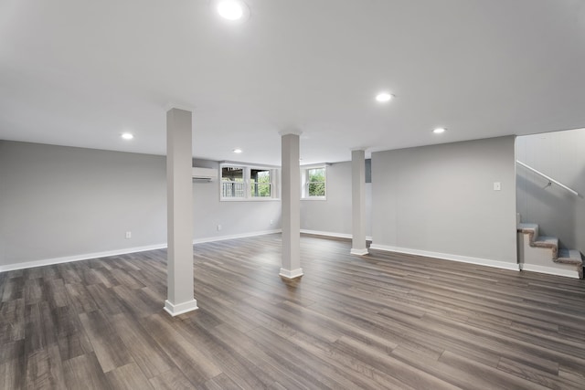 basement featuring a wall mounted air conditioner and dark hardwood / wood-style flooring