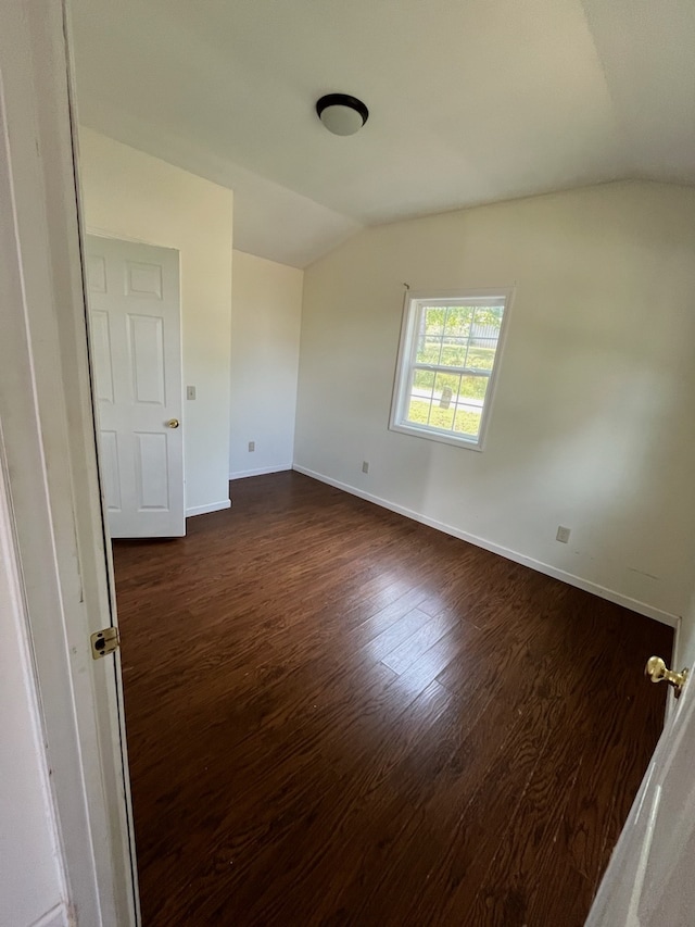 unfurnished room with lofted ceiling and dark wood-type flooring