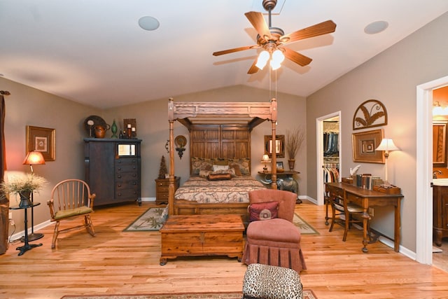 bedroom featuring ceiling fan, vaulted ceiling, ensuite bathroom, light hardwood / wood-style floors, and a walk in closet