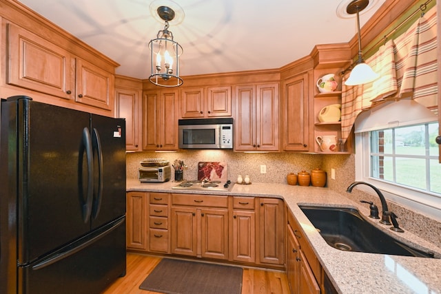 kitchen featuring sink, white gas stovetop, light hardwood / wood-style floors, decorative light fixtures, and black refrigerator