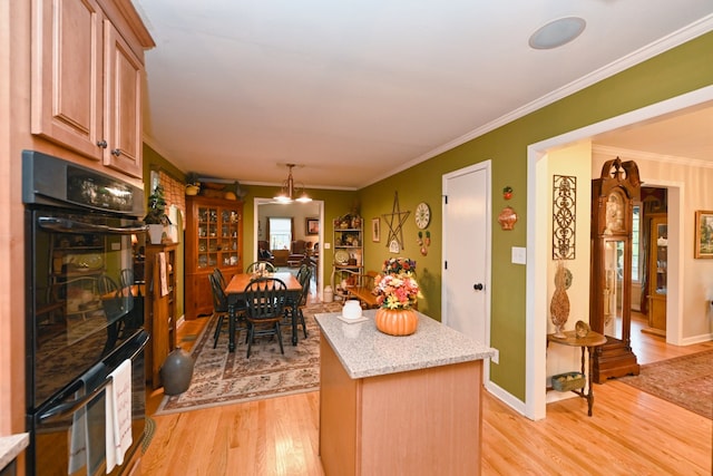 kitchen with light hardwood / wood-style floors, ornamental molding, double oven, and a center island