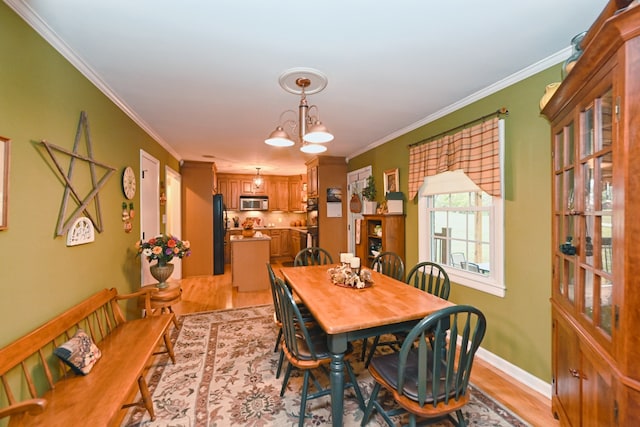 dining area with an inviting chandelier, ornamental molding, and light wood-type flooring