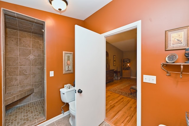 bathroom with toilet, hardwood / wood-style floors, and tiled shower