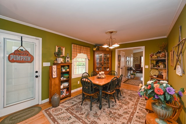 dining space featuring crown molding, a notable chandelier, and hardwood / wood-style flooring