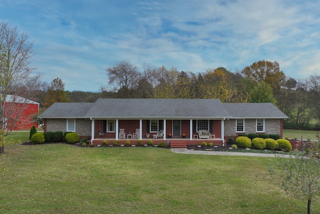 ranch-style house featuring covered porch and a front lawn