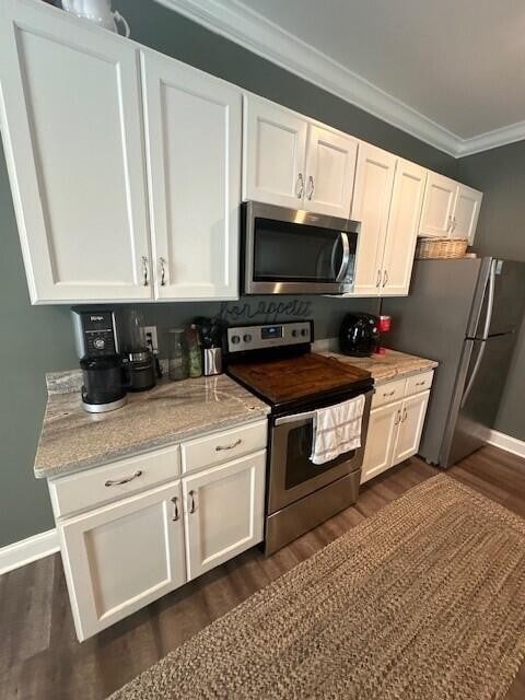 kitchen with white cabinets, appliances with stainless steel finishes, light stone countertops, dark wood-type flooring, and crown molding