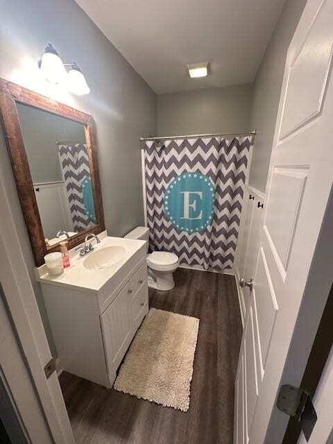 bathroom with toilet, a shower with curtain, vanity, and wood-type flooring