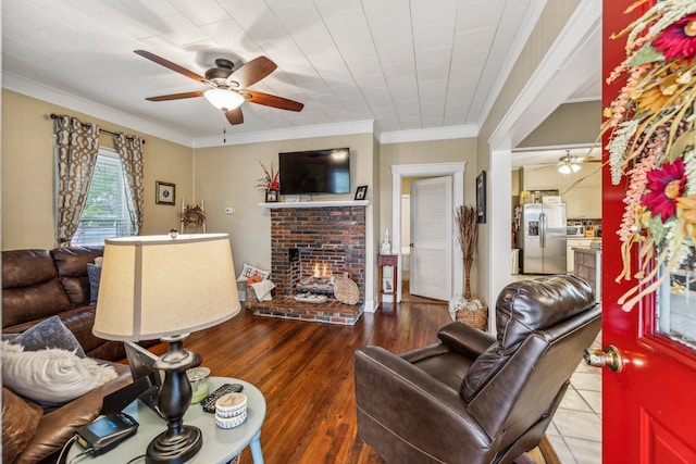 living room with ornamental molding, hardwood / wood-style floors, a fireplace, and ceiling fan