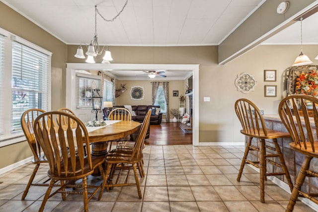 tiled dining room featuring crown molding and ceiling fan with notable chandelier