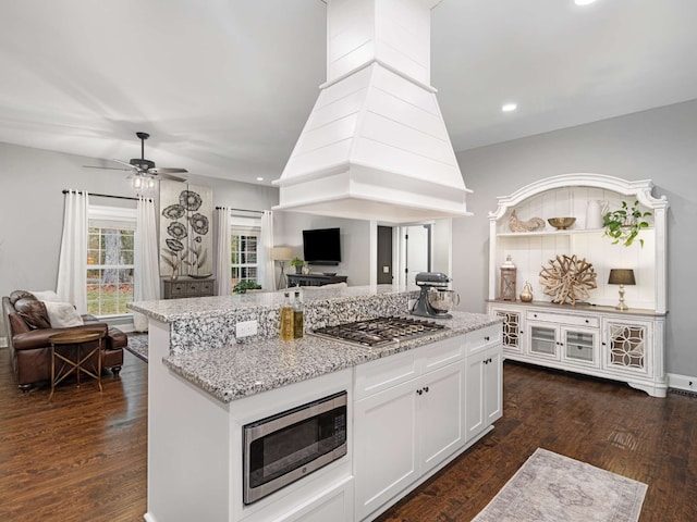 kitchen with light stone countertops, appliances with stainless steel finishes, dark hardwood / wood-style flooring, ceiling fan, and white cabinetry