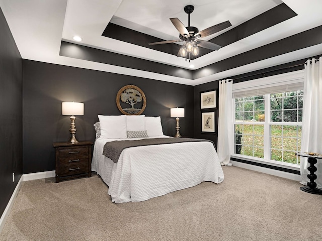 carpeted bedroom with a tray ceiling and ceiling fan