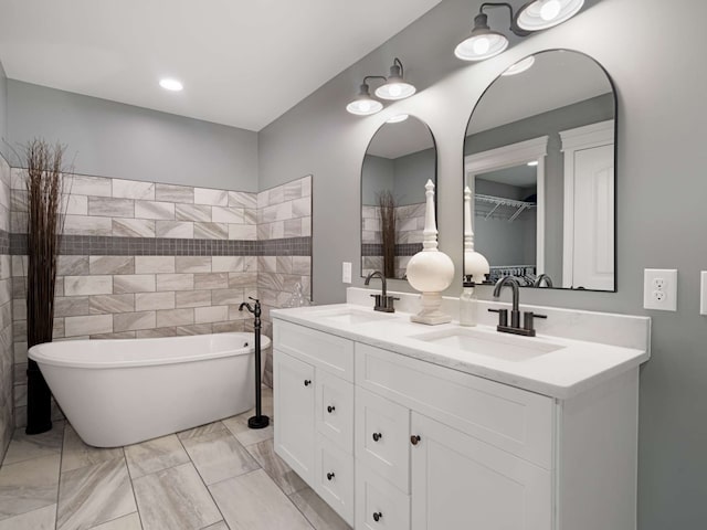 bathroom with a bathing tub, vanity, and tile walls