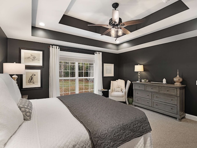 carpeted bedroom featuring ceiling fan and a tray ceiling