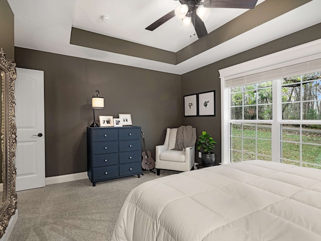 carpeted bedroom featuring ceiling fan and a tray ceiling