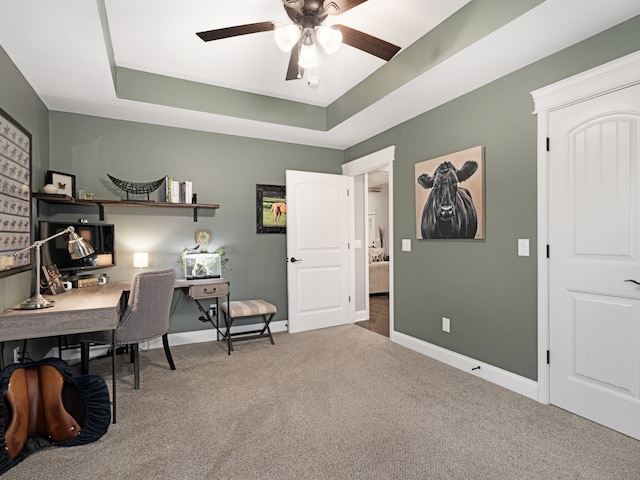 home office with carpet, a raised ceiling, and ceiling fan