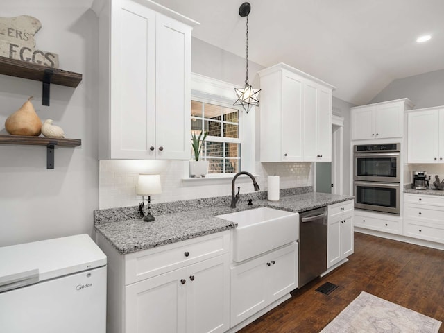 kitchen featuring decorative backsplash, white cabinetry, lofted ceiling, and appliances with stainless steel finishes