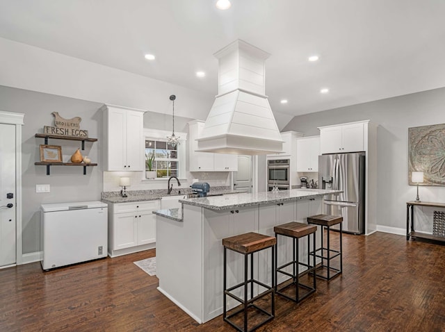 kitchen featuring decorative light fixtures, a kitchen island, dark wood-type flooring, and appliances with stainless steel finishes