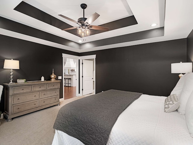 carpeted bedroom with a tray ceiling and ceiling fan