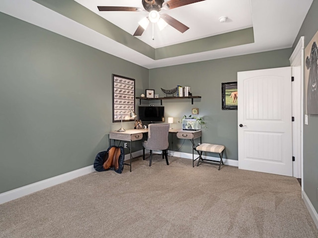 office area with carpet floors, a raised ceiling, and ceiling fan