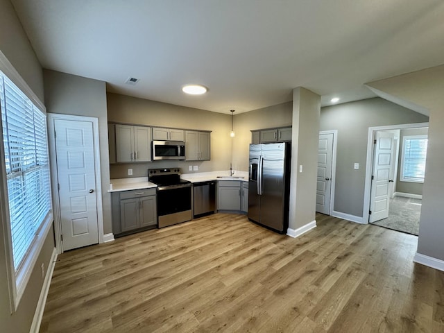 kitchen featuring gray cabinetry, hanging light fixtures, stainless steel appliances, and sink