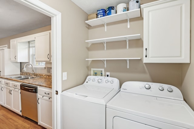 laundry room with sink, separate washer and dryer, a textured ceiling, light hardwood / wood-style floors, and cabinets