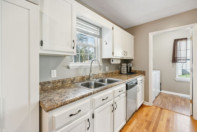 kitchen featuring light hardwood / wood-style flooring, sink, stainless steel dishwasher, white cabinets, and washing machine and clothes dryer