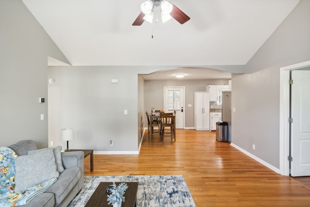 living room featuring light hardwood / wood-style flooring, vaulted ceiling, and ceiling fan