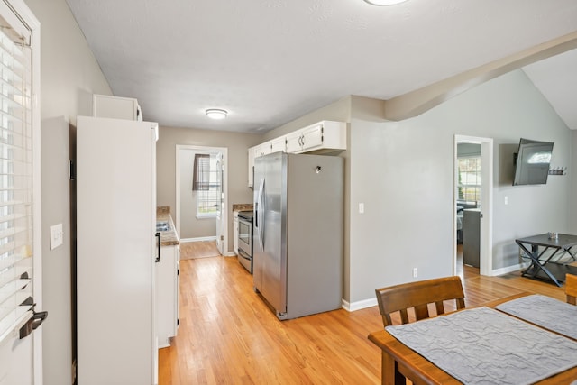 kitchen with lofted ceiling, white cabinetry, stainless steel appliances, and light wood-type flooring