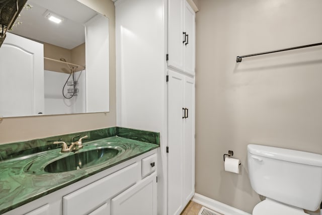 bathroom featuring toilet, vanity, and a shower