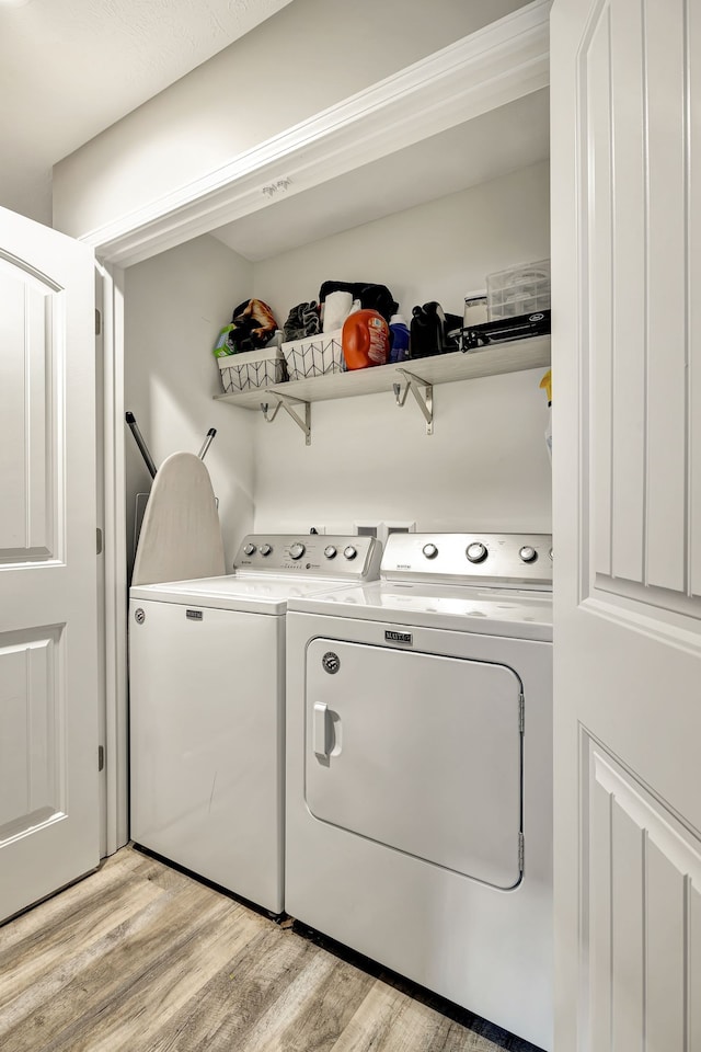 clothes washing area with light hardwood / wood-style flooring and washer and dryer